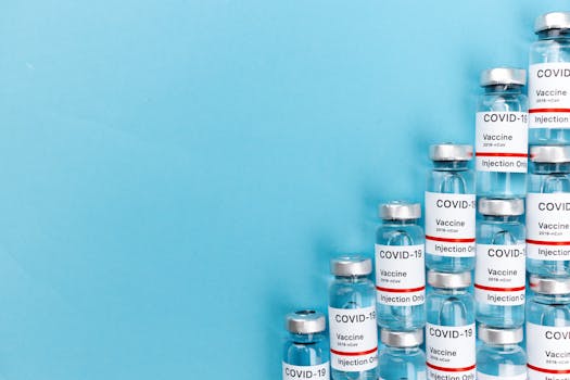 A row of COVID-19 vaccine vials arranged on a blue background illustrating pandemic response.