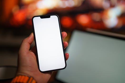 Blank smartphone screen held by a person in a warm and cozy indoor environment, suitable for mockups.