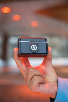 Close-up of a hand holding a small electronic device outdoors. Perfect for technology themes.