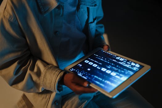 Close-up of a person using a tablet device indoors with code visible on the screen.