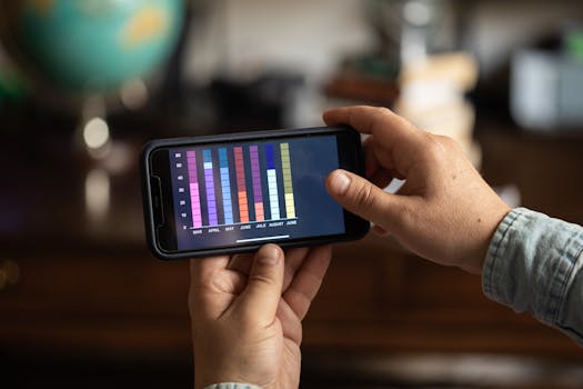 Close-up of hands holding a smartphone displaying a colorful bar graph. Perfect for business and technology themes.