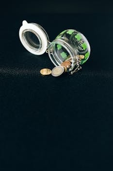 An open jar spilling coins, representing financial concepts on a black backdrop.