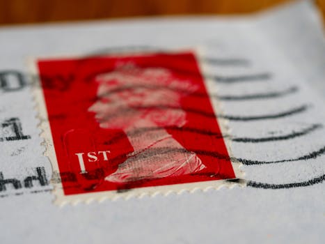 Detailed view of a red first-class postage stamp with a visible postmark.